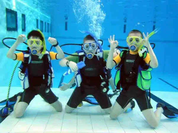 Young Bubblemaker diver smiling underwater with a PADI instructor